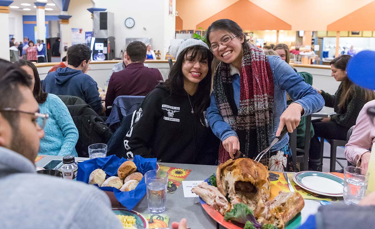 Two students slicing turkey at Servo Thanksgiving Dinner