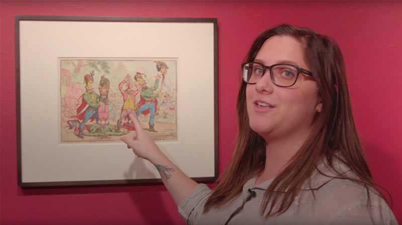 Headshot of Bailey Harper in an art gallery explaining a satirical art print