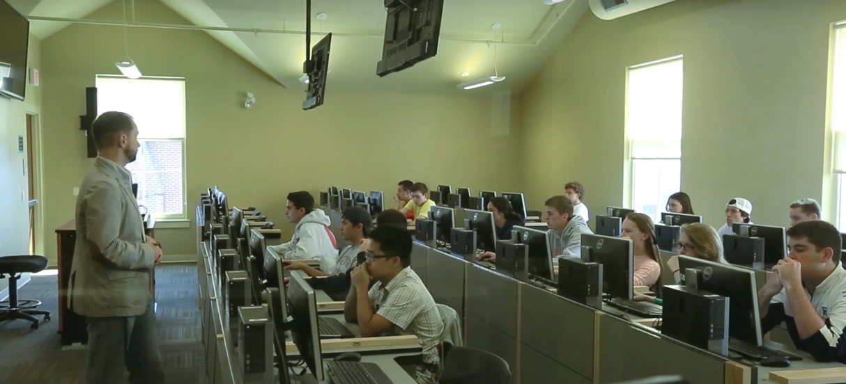 Professor and students sitting in an economic lab