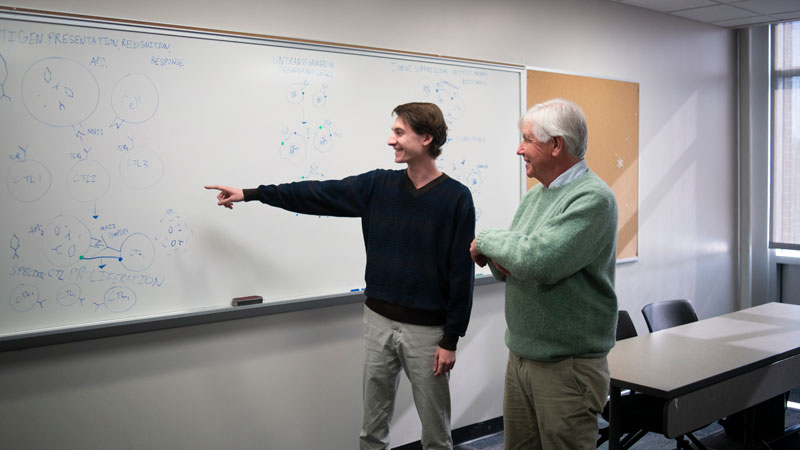Matthew Cherubino in the classroom pointing at a white board