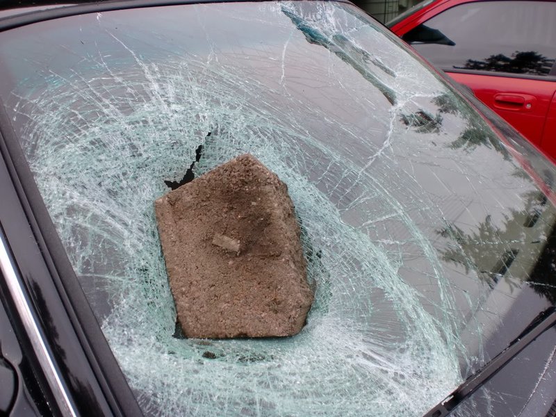 A rock on a broken glass of the front of a car
