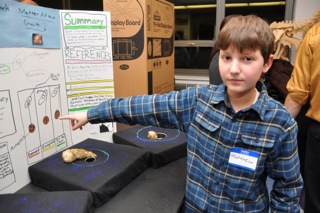 A boy pointing at a science poster at a grade 6 Science Fair