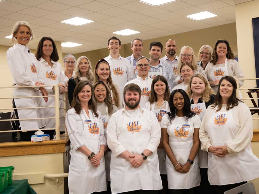 College Advancement team members wearing aprons and posing for a photo inside the cafeteria