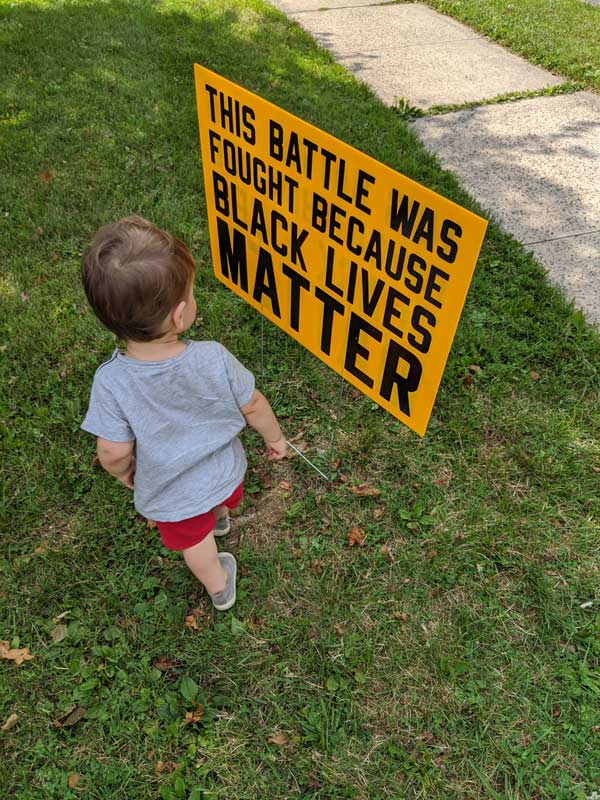 Amanda Heim's young son stands in front of a yard sign in her front yard