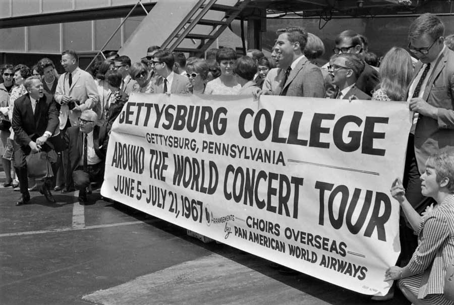 Members of the Gettysburg College Choir holding a banner with language about a world tour