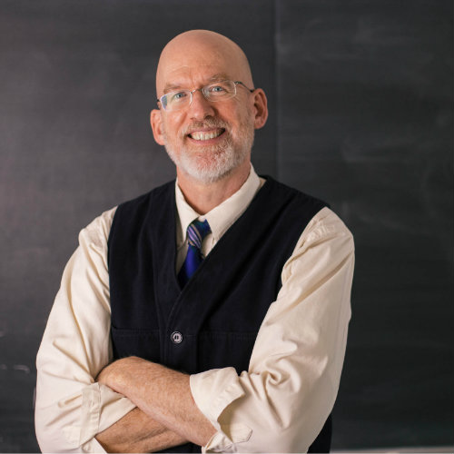 Chris Fee standing in front of a chalkboard.