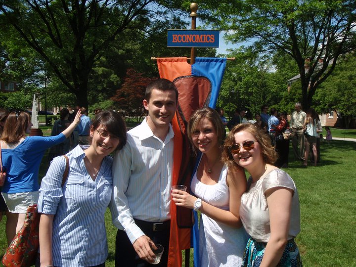 Svet Semov posing with friends and the Economics Department banner during Commencement.
