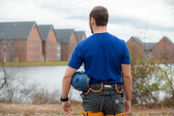 A man stands with a helmet under his arm.