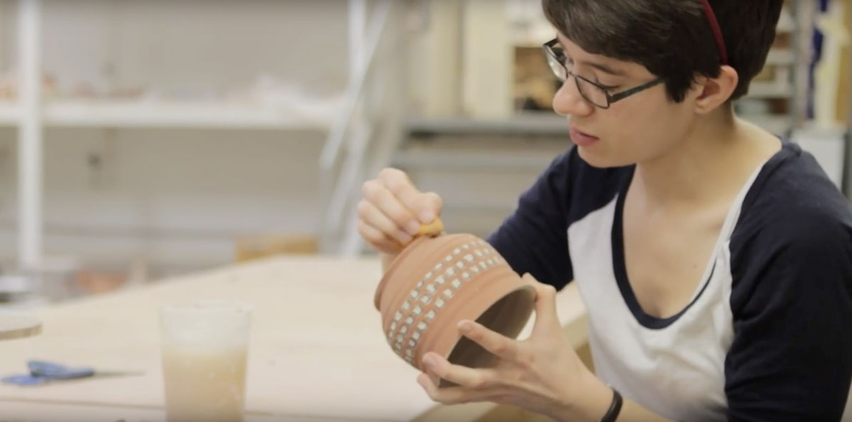 A student polishing her pottery in the Art Studio