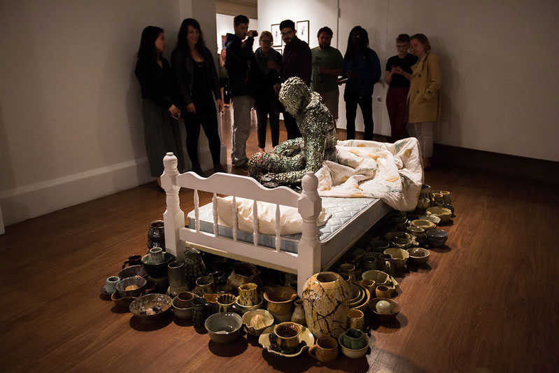 Photo of sculpture of a person on a bed in an art gallery