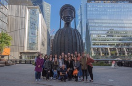 Art department students posing for a picture in front of a large sculpture of a woman
