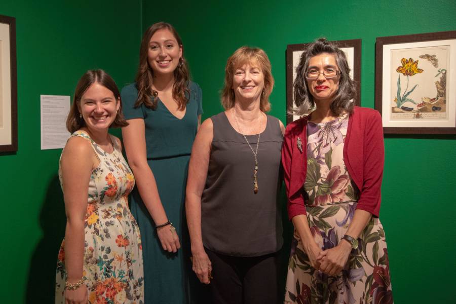 Group standing in a gallery with botanical prints on green walls.