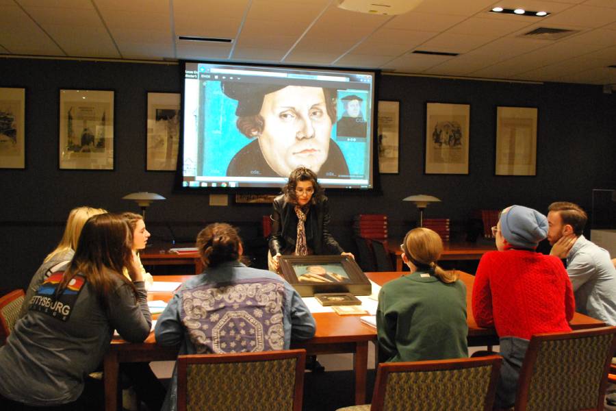 Professor leads a seminar with a portrait of Martin Luther projected behind.