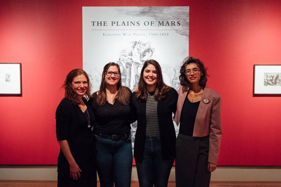 Four women stand in front of a museum exhibition titled The Plains of Mars.