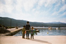 Photo of three children standing in front of the water