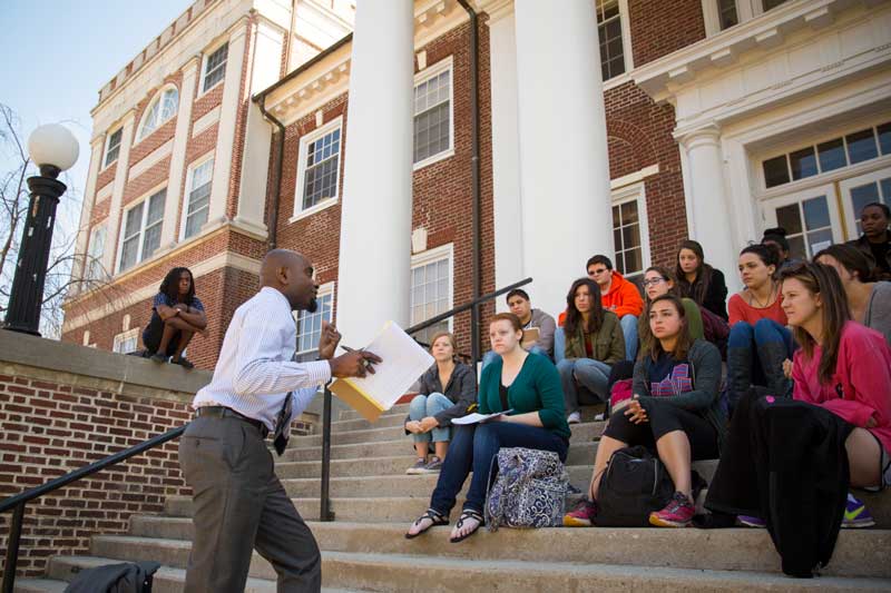 Faculty member lecturing students outside on the steps of a building