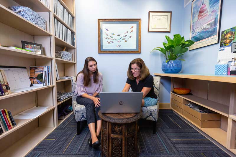 Faculty member and student sitting with one another in an office setting