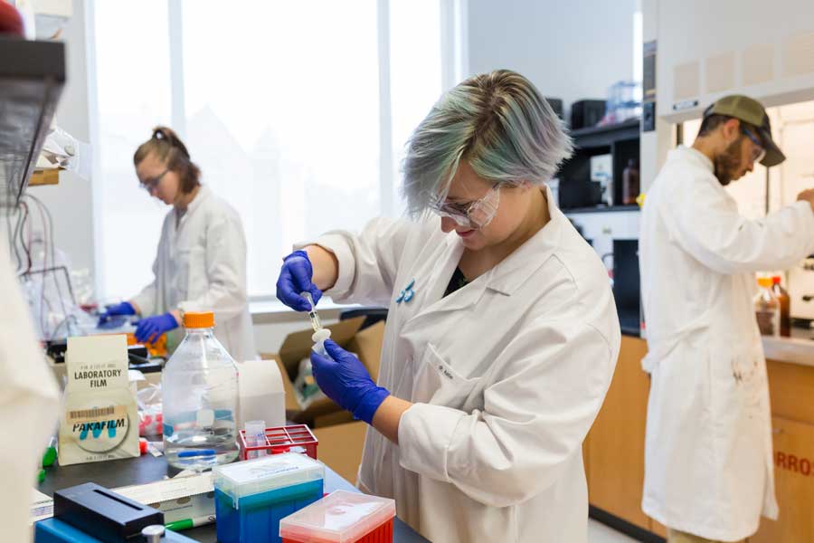 Student working in a lab with a white coat