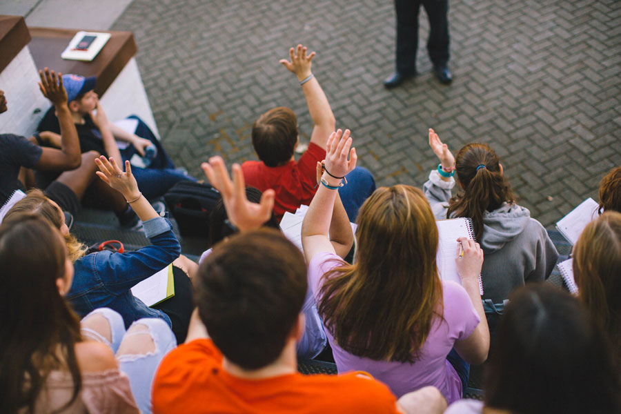 Students sitting and raising their hands in the air