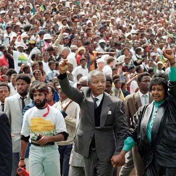 Photo of Nelson Mandela in front of a crowd with his fist raised