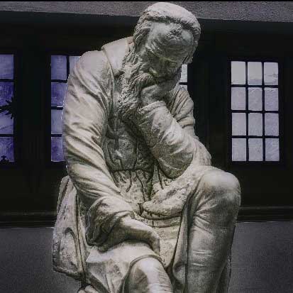 Statue of a man sitting with his hand on his face