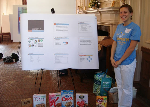 Courtney Cele ’ 09 standing next to her poster