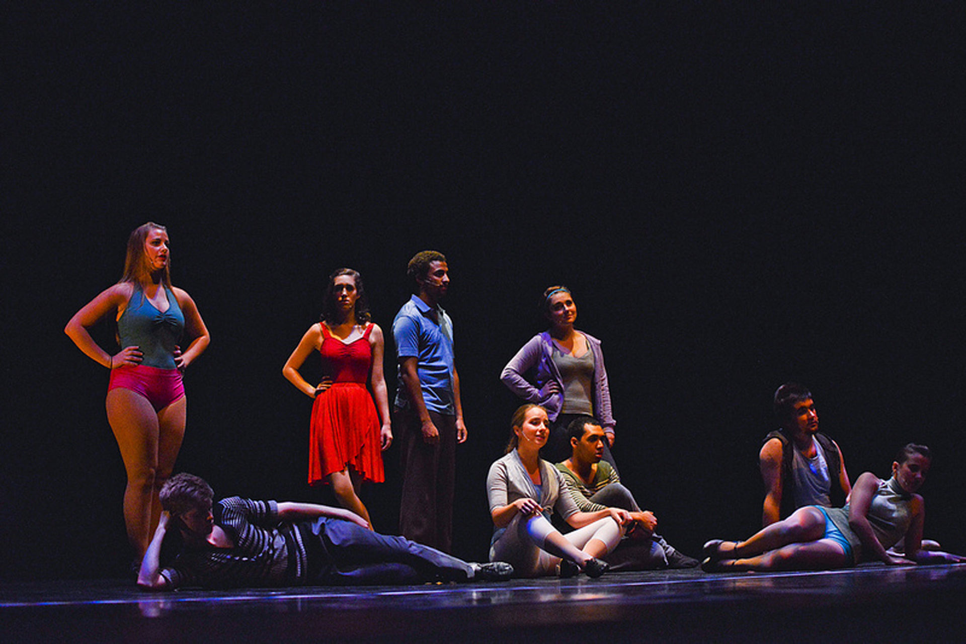 Actors and actresses standing and sitting with a dark background