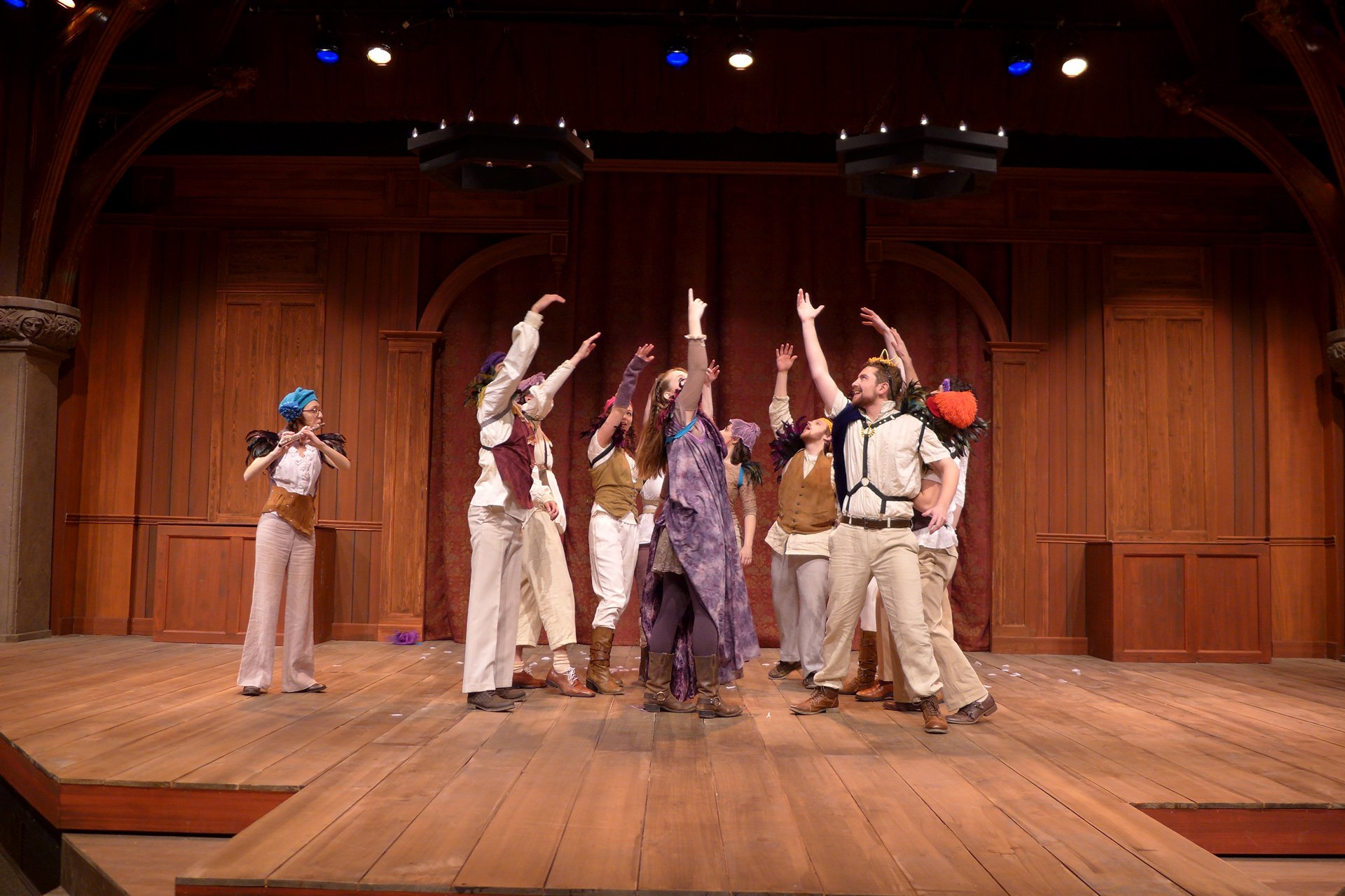 Actors and actresses holding their hands in the air and standing in a circle