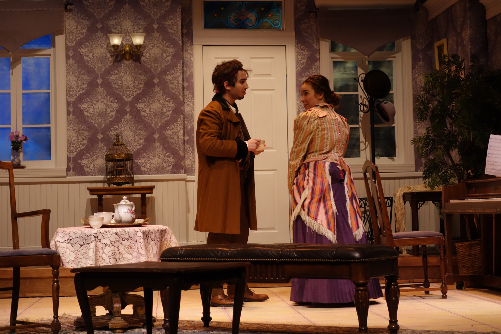 Actor and actress in period attire standing together in a victorian room