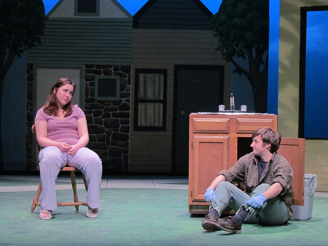 Actor and actress sitting down in a suburban setting