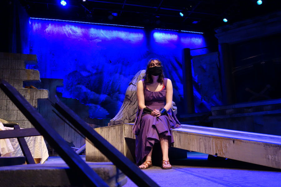 Woman sitting on a prop wearing a purple dress with blue background lighting