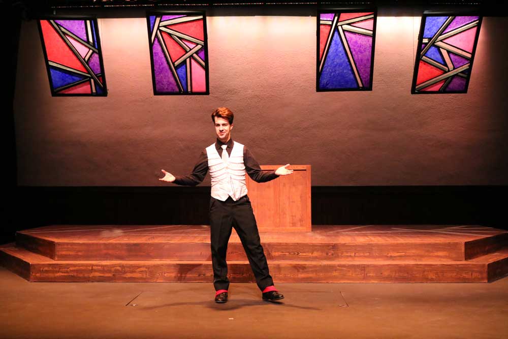 Man standing on stage with his arms raised