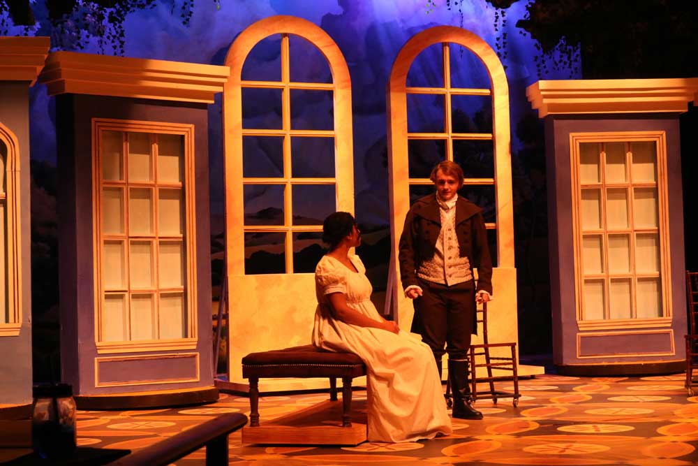 Male actor standing next to a sitting female actress dressed in Victorian attire