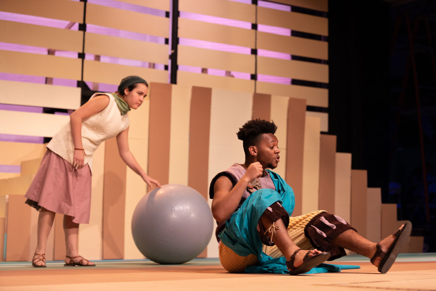 A man and woman on stage with a yoga ball