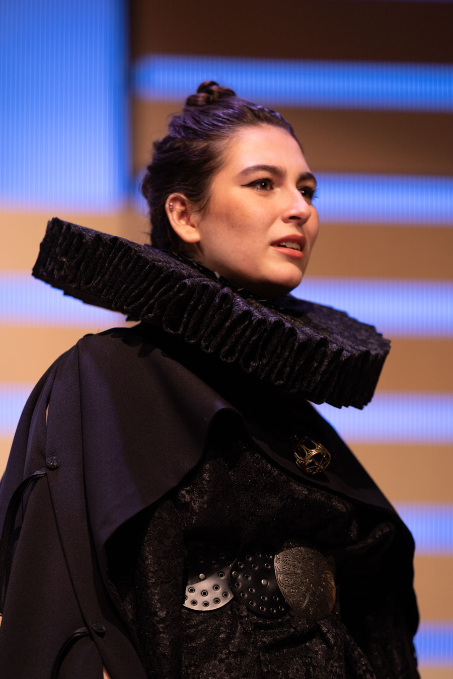 A close up of a womans face wearing renaissance era clothing