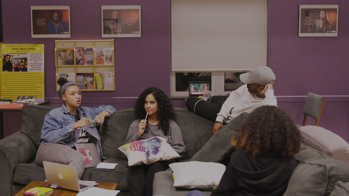 Destiny Familia sitting with her friends on a grey sofa