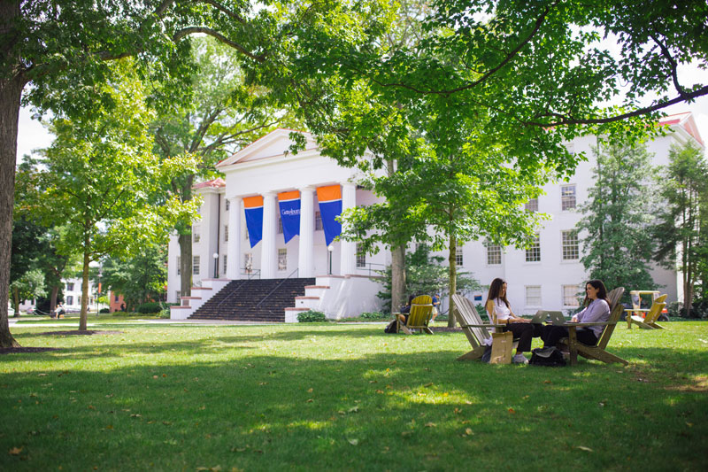 students sitting with laptops in front of Penn Hall