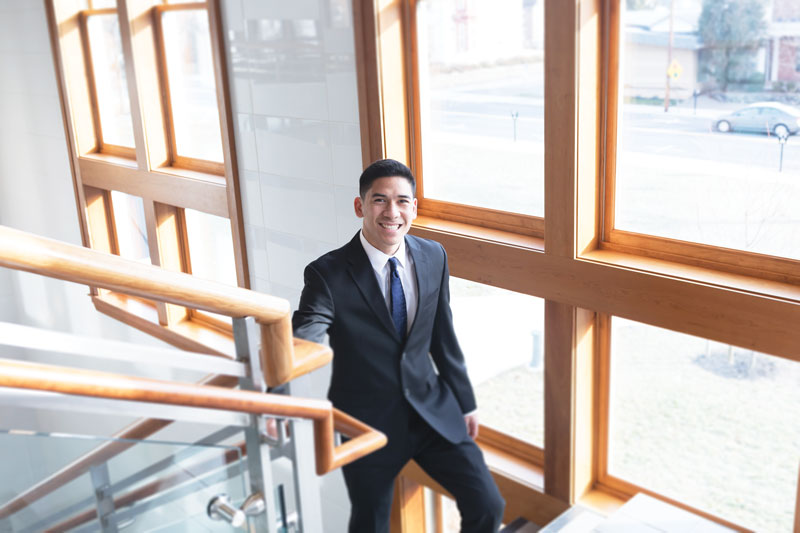 Kevin Benavente wearing a suit and posing on a stairwell