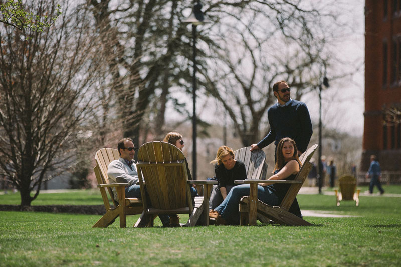 Parents and students sitting in adirondack chairs on campus