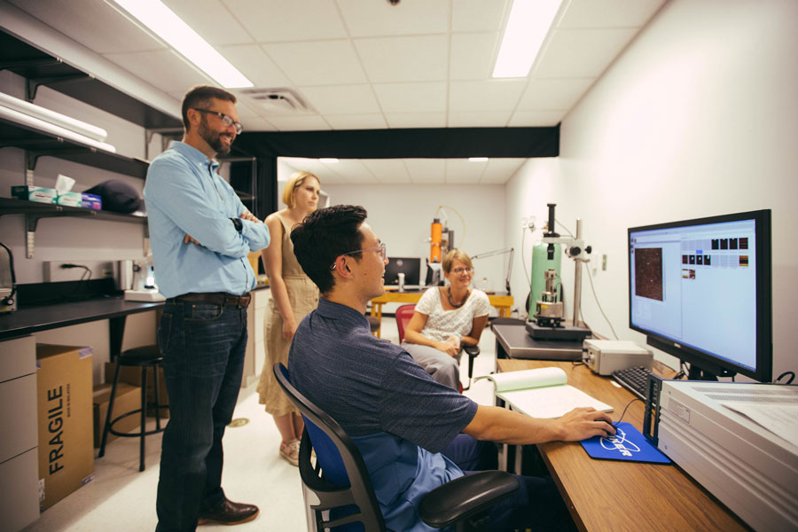 Student in classroom with teachers in front of a computer