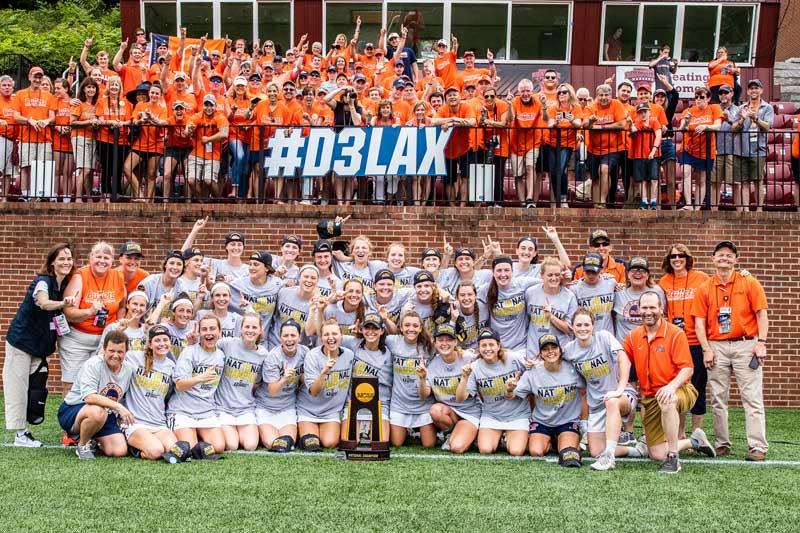 Women's lacrosse players posing for a photo with a trophy