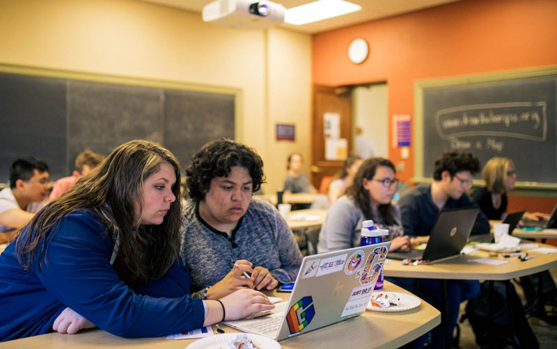 Two students looking at a laptop screen in class