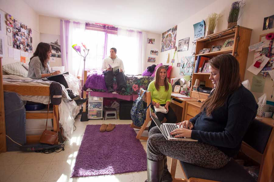 Three female students and a male student studying together in a residence hall