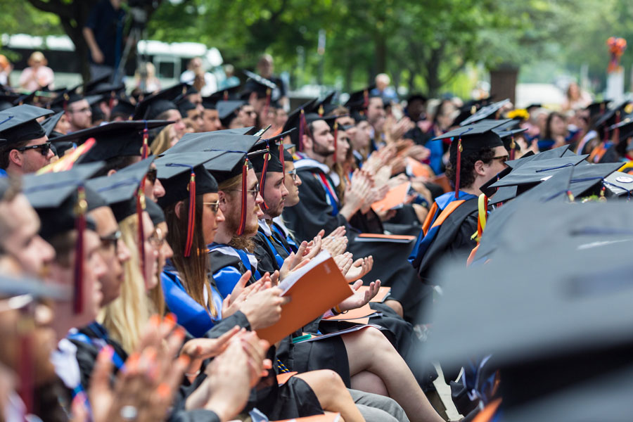 Students in their Commencement regalia clapping