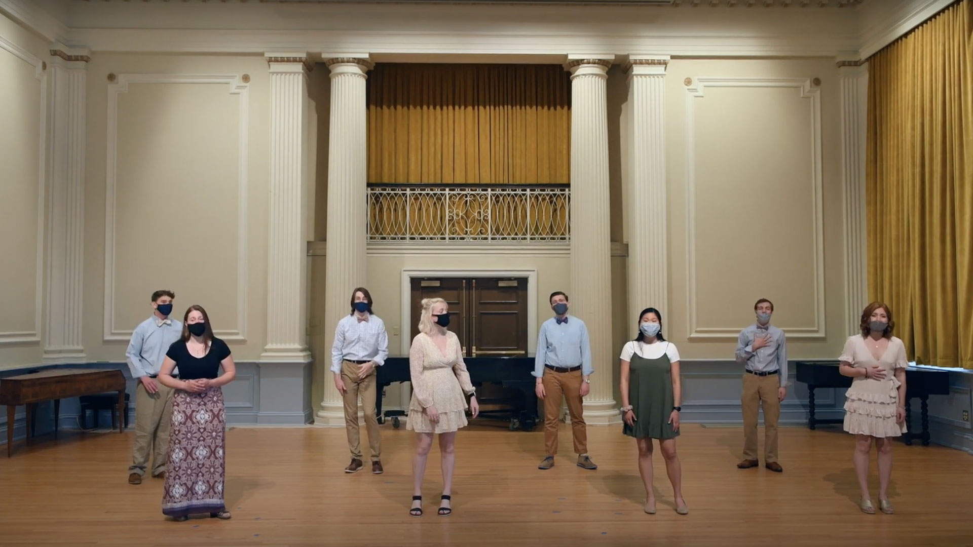 Students standing distanced apart on a stage with masks on