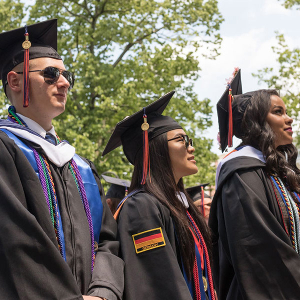 Graduates standing and looking up towards Beachem Portico at a Commencement ceremony
