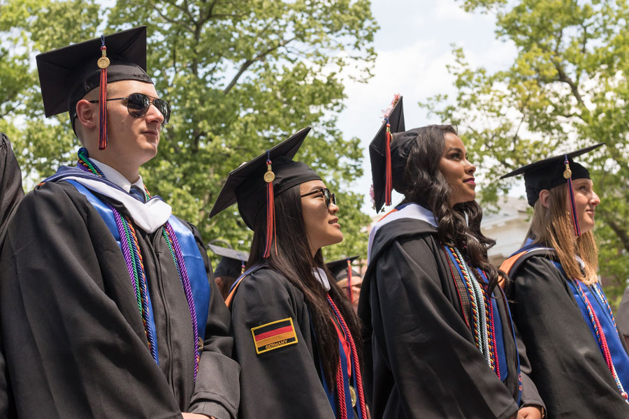 Graduates standing and looking up towards Beachem Portico at a Commencement ceremony