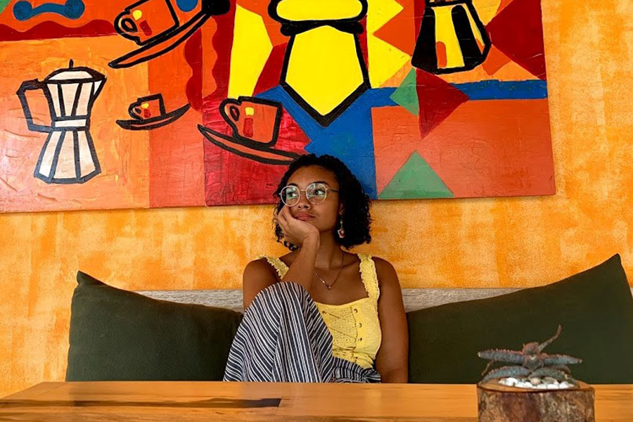 Woman sitting inside of a coffee shop with bright colored decor