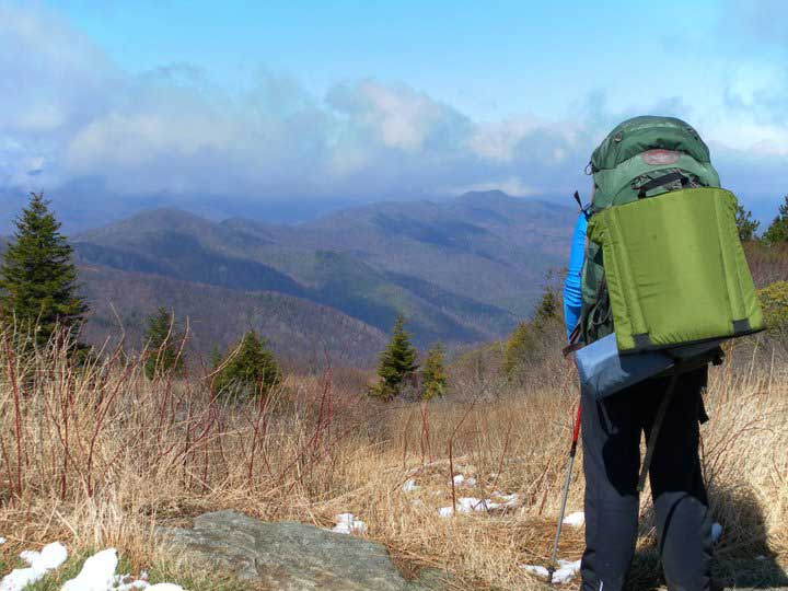 Person hiking with a backpack in front of a mountain range