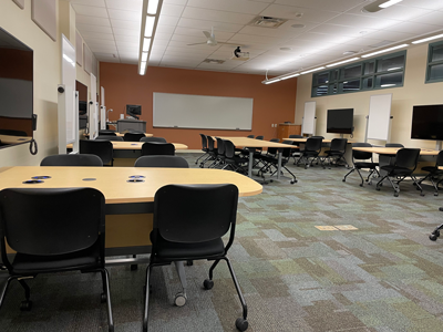 014 classroom with 5 workstation pods with seating for four and 6 wheeled tables in the center of the room